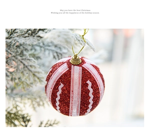Detail der roten Glitzer-Weihnachtskugel mit weißem Band auf verschneiten Tannenzweigen