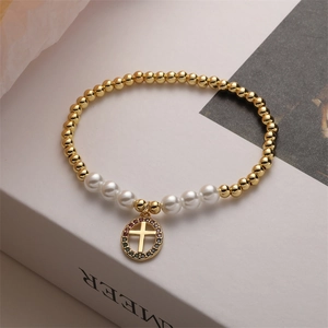 Detailed macro view of beaded bracelet with golden cross pendant and colored crystals