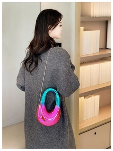 Model wearing a gradient cyan to pink acrylic U-shaped clutch bag with gold chain strap