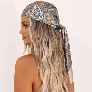 Close-up of bohemian orange paisley silk satin square headscarf tied on model hair