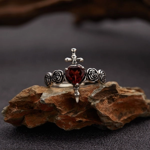 Macro detail of gothic S925 silver ring with red heart garnet and sword motifs