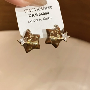 Macro shot of star-shaped earrings with cat relief and zircon on 18k gold plating