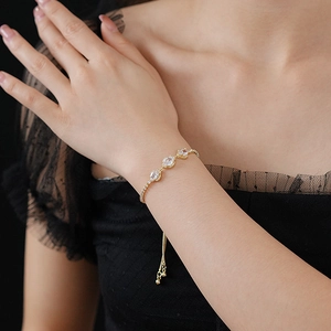 Detail of adjustable gold bracelet with oval zircon stones on a model wrist