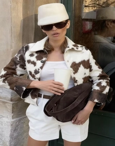 Détail d'une veste courte présentant un imprimé vache texturé et fausse fourrure