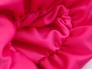 Detailansicht des rosaroten elastischen Stoffes mit eleganten Falten und Knittereffekt