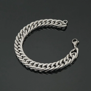 Men's silver stainless steel Cuban link bracelet with lobster clasp on a black surface
