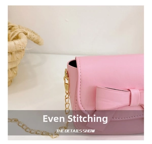 Close-up of pink girls crossbody bag with bow decoration and gold chain strap detail