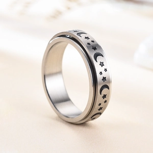 Macro shot of spinner ring with etched moon star pattern and brushed steel texture