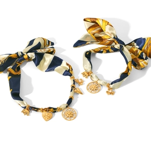 Baroque silk ribbon bracelet with golden elephant sun and heart charms on white background