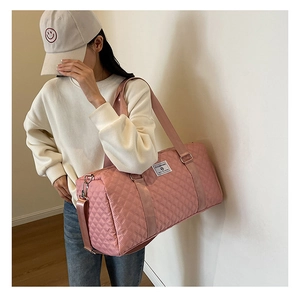 Vue détaillée du sac de voyage matelassé rose avec sangle porté par un mannequin