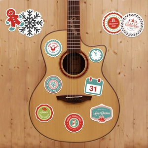 Christmas stickers with Santa and snowflakes decorating a light wood acoustic guitar