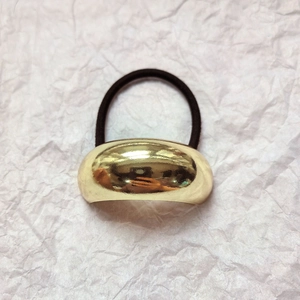 Close-up of a gold metal half-cylinder buckle with black high-elastic hair band
