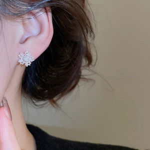 Close-up of model wearing elegant silver snowflake stud earrings with cubic zirconia stones