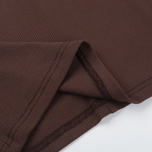 Macro du tissu en maille côtelée marron foncé montrant les coutures et l'ourlet précis
