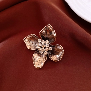 Detailed macro view of vintage flower brooch with rhinestone center on red satin