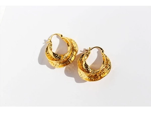 Detailed view of golden hoop earrings featuring unique irregular hammered metal textures