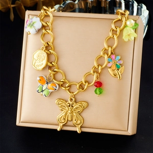 Detail of gold beaded bracelet featuring enamel butterfly and flower charms on a beige pad