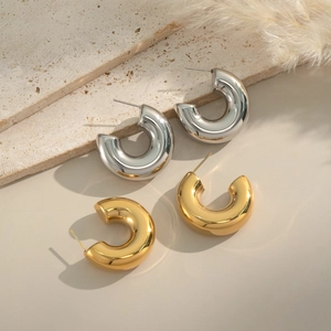 Gros plan de boucles d'oreilles créoles en acier inoxydable or et argent sur pierre