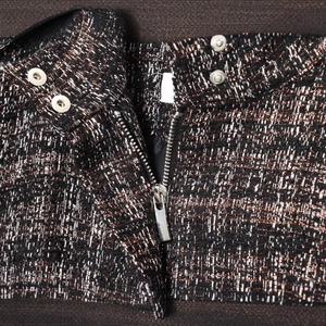 Close-up of metallic tweed bomber jacket featuring high-quality zipper and button details