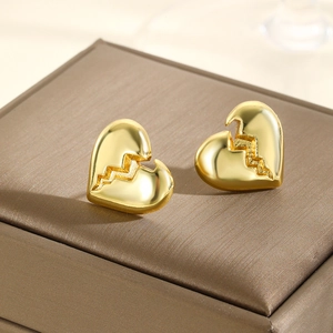 Macro detail of gold geometric heart earrings with lightning crackle on a leather box