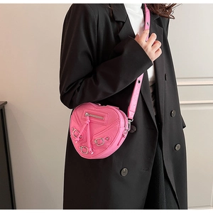 Détail du sac à bandoulière rose en forme de cœur avec clous et éléments de style biker