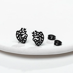 Macro shot of matte black hollow anatomical heart stud earrings on a white ceramic plate