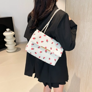 Detailed view of white strawberry pattern corduroy bag with gold chain strap on model