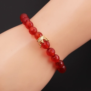 Macro shot of red 8mm faceted beads bracelet with a gold crown charm inlayed with crystals
