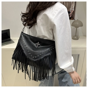 Detailed view of large black crossbody bag with metal rivets and long fringe details
