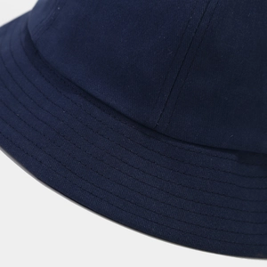 Gros plan sur le coton sergé bleu marine et les coutures renforcées du chapeau bob