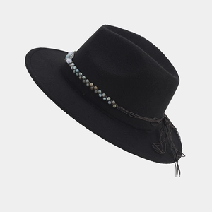 Detalle de sombrero de fieltro negro con banda étnica de cuentas, hoja de metal y flecos
