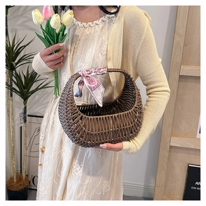 Brown woven basket bag with pink ribbon handle held in a cozy lifestyle setting