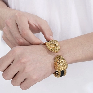 Close-up of golden men's cuff bracelet featuring lion head relief and braided wire texture