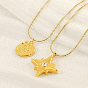 Detailed macro view of gold compass coin and star pendant on a snake chain