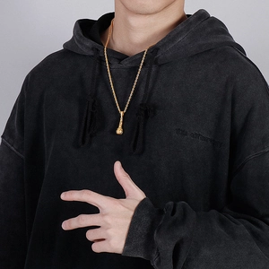 Dettaglio del ciondolo a microfono in oro hip hop con cristalli indossato da modello