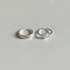 Macro shot of 925 sterling silver smile face and heart rings with adjustable open band