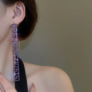 Dettaglio di orecchini pendenti in argento con cristalli viola e decorazioni geometriche interne
