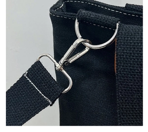 Detailed close-up of durable metal hooks and D-ring hardware on a black canvas tote bag