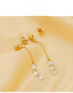 Detail of gold tassel earrings in titanium steel with clear cubic zirconia accents