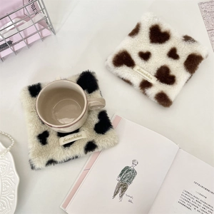Macro detail of plush heart pattern coaster with soft texture and woven label