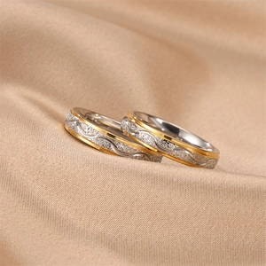 Detailed view of titanium steel couple rings featuring frosted texture and wavy gold accents