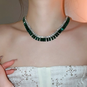 Macro shot of silver-tone necklace with vertical emerald-cut green stone and tiny rhinestones