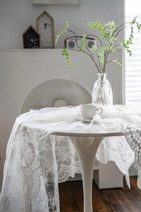Detailed close-up of white lace tablecloth with elegant floral patterns on a table