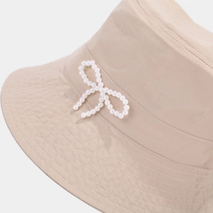 Beige quick-dry bucket hat featuring a delicate white pearl bow and reinforced stitching
