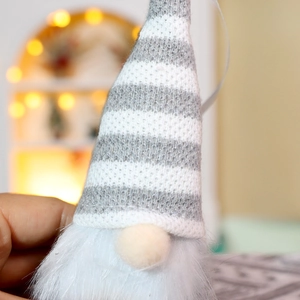 Detail of grey and white striped knitted gnome hat with soft plush faux fur beard texture