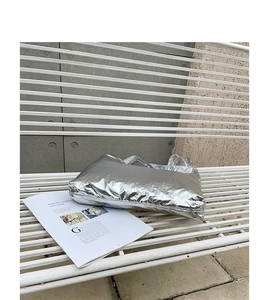 Close-up of metallic silver nylon handbag with wrinkled texture on a white bench