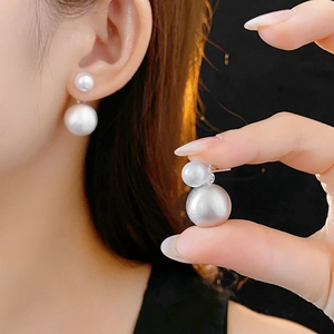 Detailed view of double-sided white pearl stud earrings on model for elegant styling