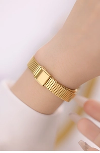 Detail of elegant gold mesh watch band with secure folding clasp on female wrist