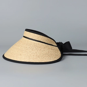 Detail of raffia sun hat showing woven texture, black ribbon edge, and bow tie
