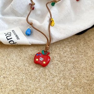 Gros plan détaillé du pendentif pomme rouge avec des perles colorées sur cordon